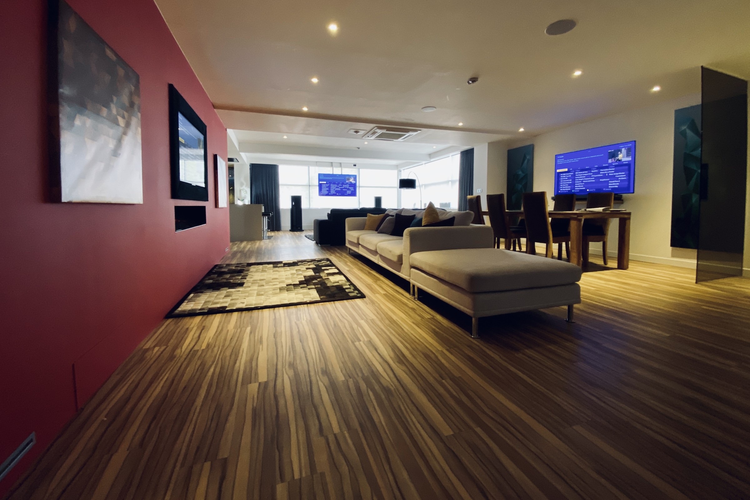 Smart home lounge area with motorised drop-down TV, floor-standing speakers and furniture