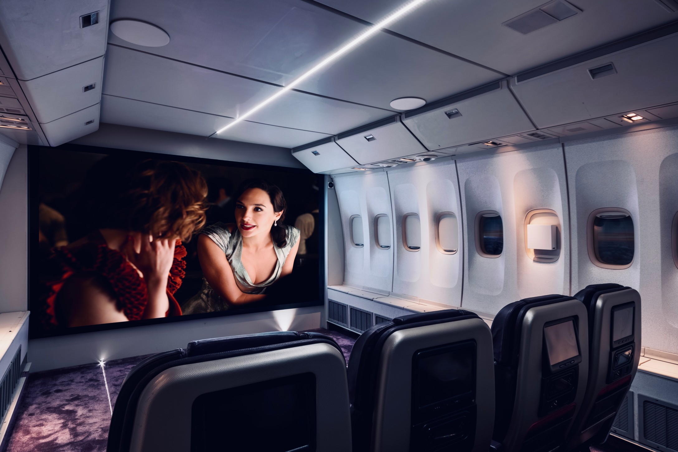 Home Cinema room made from decommissioned aircraft showing movie on projector screen, lighting, and aircraft chairs